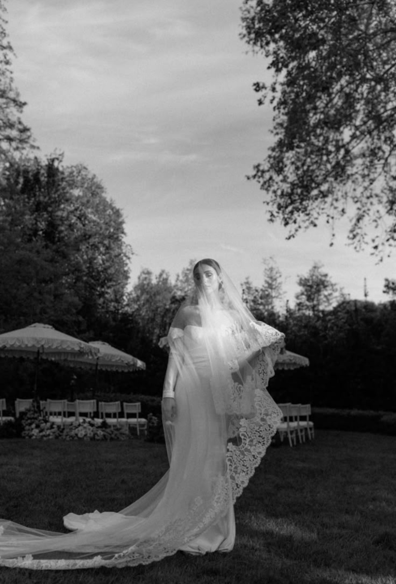 Bride standing beneath a veil in a garden